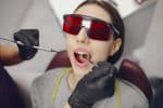 a lady is having charcoal teeth whitening treatment