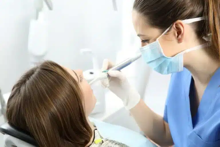 a woman is getting air polishing treatment from a dentist