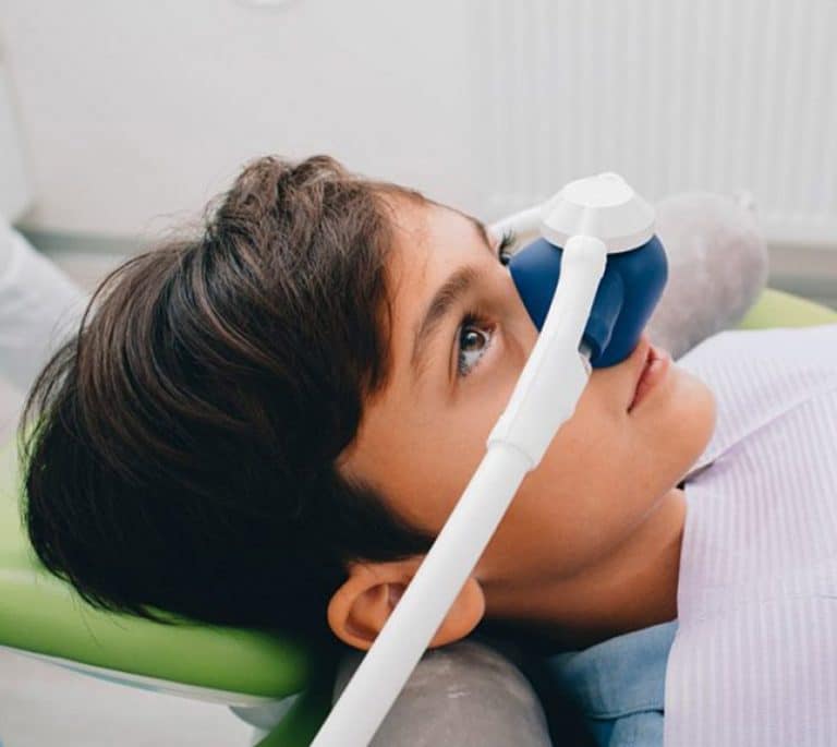 a child is lying on bed and having sedation dentistry treatment